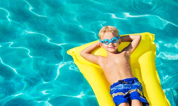Chłopiec relaksu i zabawy w basenie na tratwie żółty — Zdjęcie stockowe
