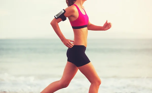 Mujer deportiva corriendo en la playa al atardecer —  Fotos de Stock