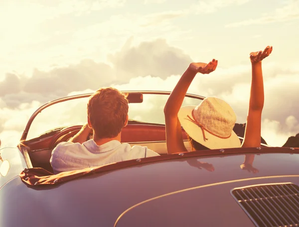 Jeune couple Wathcing le coucher du soleil dans la voiture de sport Vintage — Photo