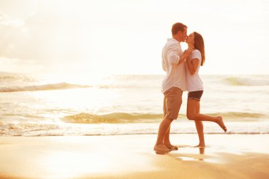 Romantik Çift gün batımında sahilde öpüşme