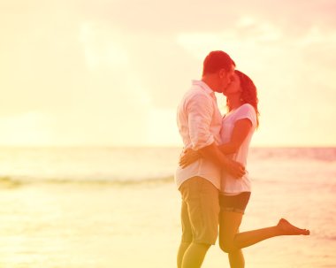 Romantik Çift gün batımında sahilde öpüşme