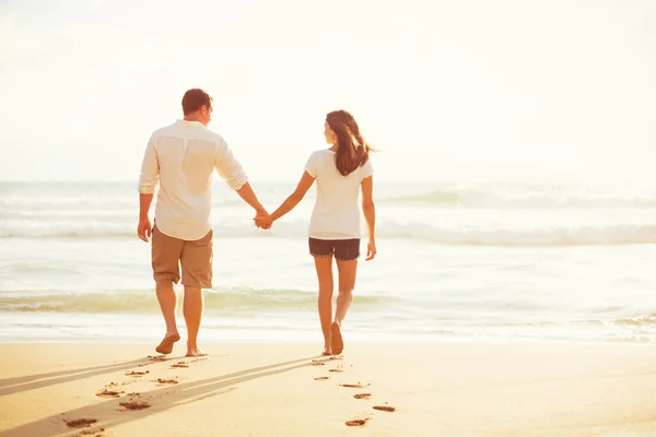 Paar wandelingen op het strand bij zonsondergang — Stockfoto