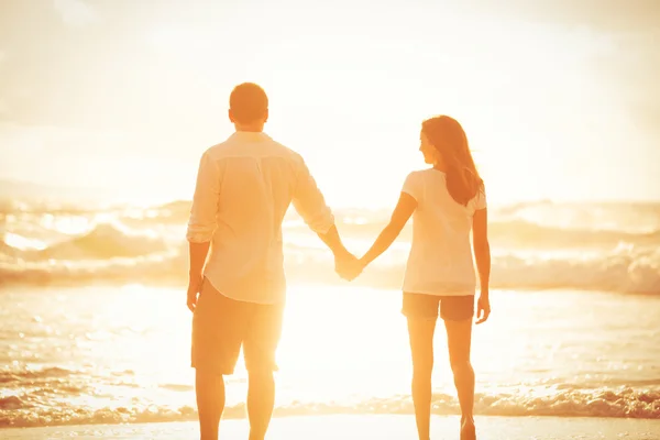 Paar spaziert bei Sonnenuntergang am Strand — Stockfoto