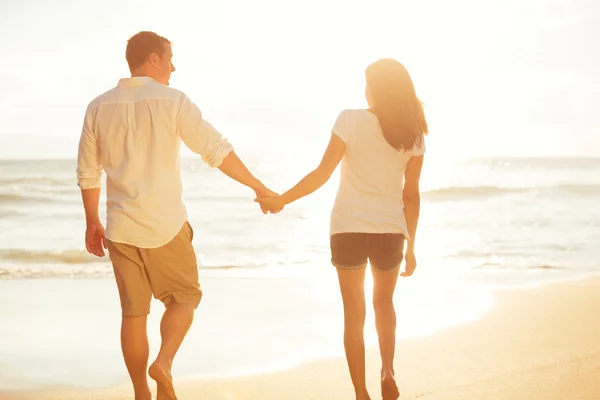 Pareja caminando en la playa al atardecer — Foto de Stock