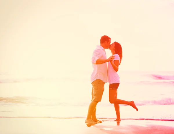 Romantiska par kyssar på stranden i solnedgången — Stockfoto