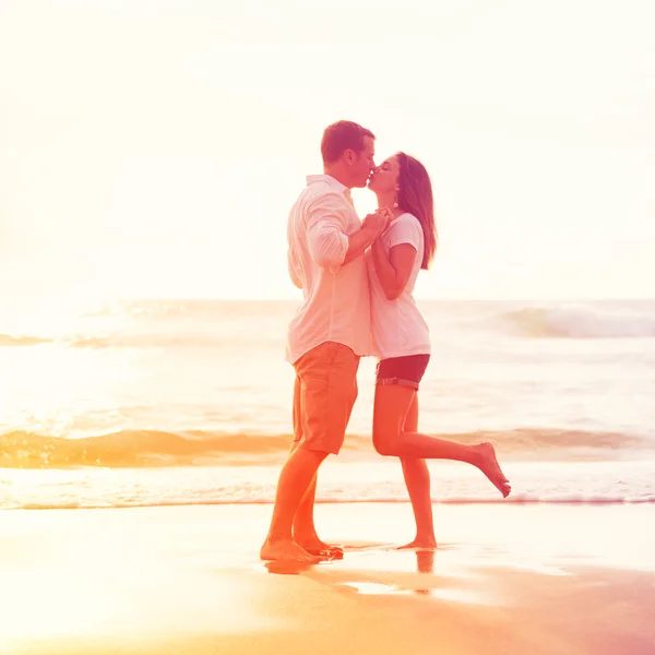 Romantisch paar zoenen op het strand bij zonsondergang — Stockfoto