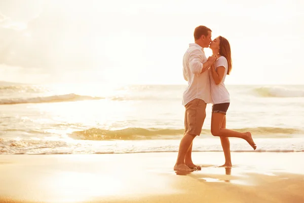 Casal romântico beijando na praia ao pôr do sol — Fotografia de Stock