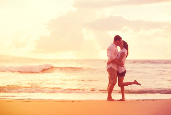 Couple romantique s'embrassant sur la plage au coucher du soleil — Photo