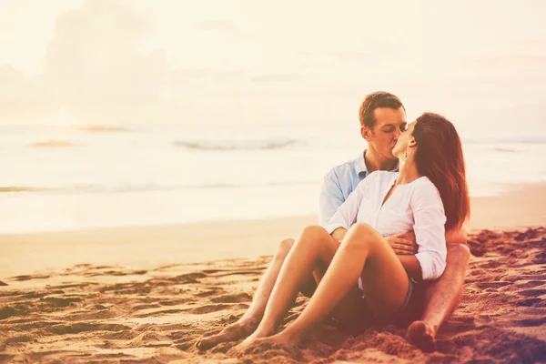 Casal romântico desfrutando de belo pôr do sol na praia — Fotografia de Stock