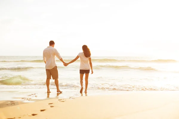 Pareja caminando en la playa al atardecer Imagen de archivo