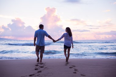 Gün batımında sahilde yürüyüş severler