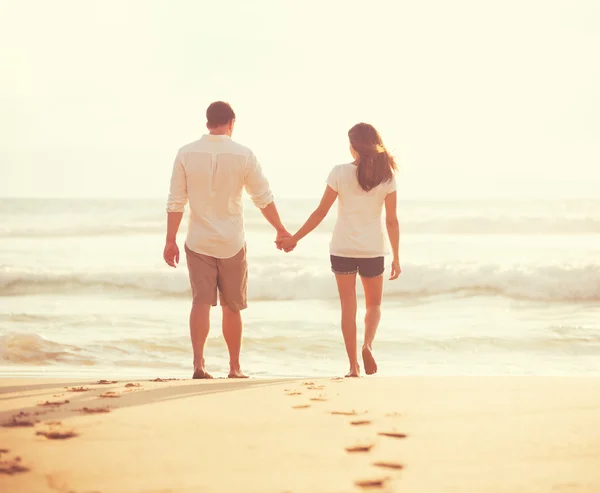 Jeunes amoureux marchant sur la plage au coucher du soleil — Photo