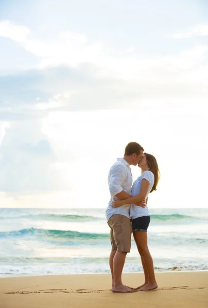 Jovem casal beijando na praia ao pôr do sol — Fotografia de Stock