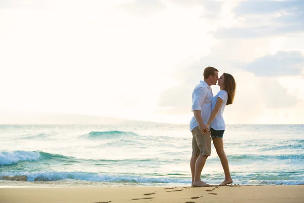 Jovem casal beijando na praia ao pôr do sol — Fotografia de Stock