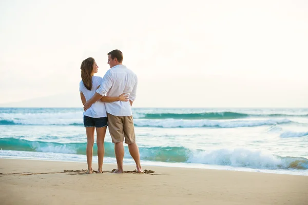 Fiatal pár a strandon naplementekor — Stock Fotó