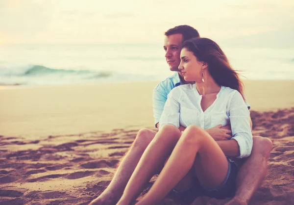 Пара отдыхает на пляже, наблюдая за закатом — стоковое фото
