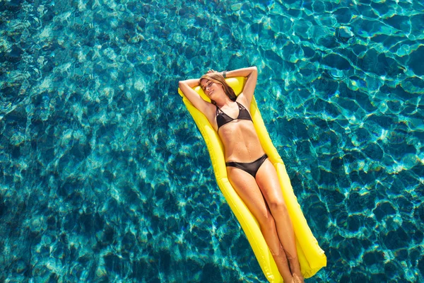 Femme relaxant flottant sur le radeau dans la piscine — Photo