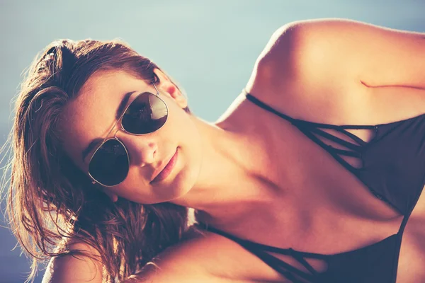 Hermosa mujer en bikini relajante junto a la piscina al atardecer —  Fotos de Stock