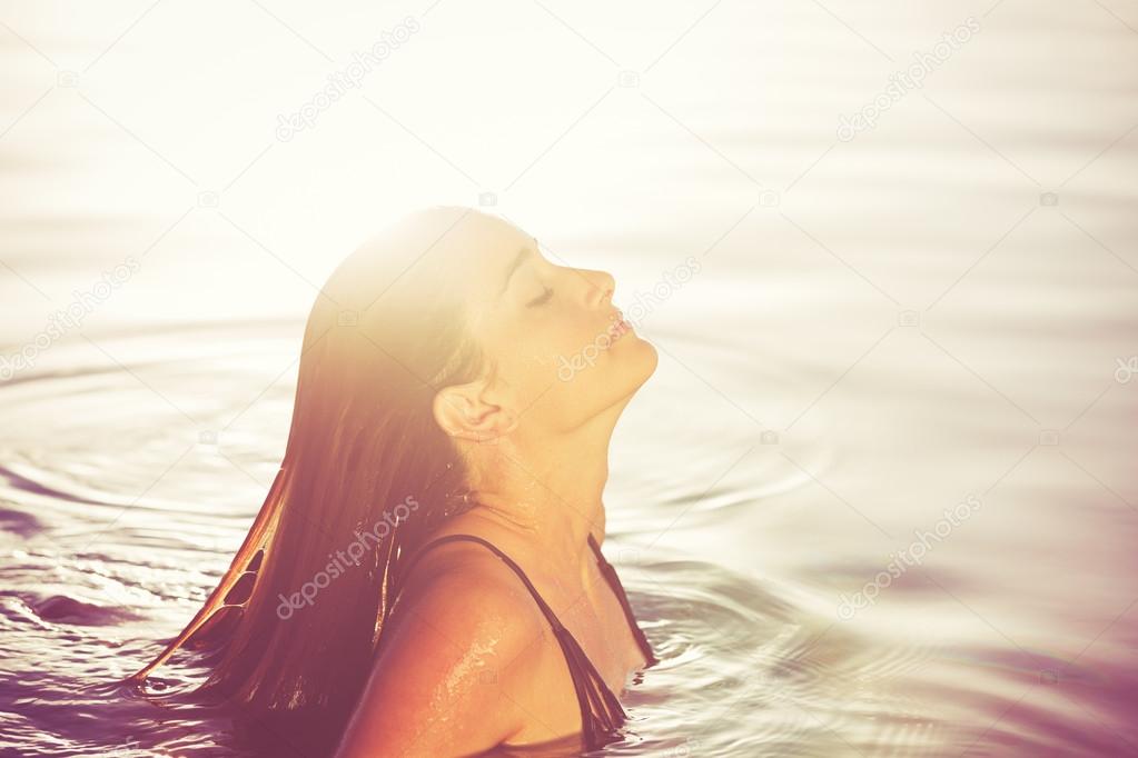 Beautiful Woman Relaxing in Pool at Sunset