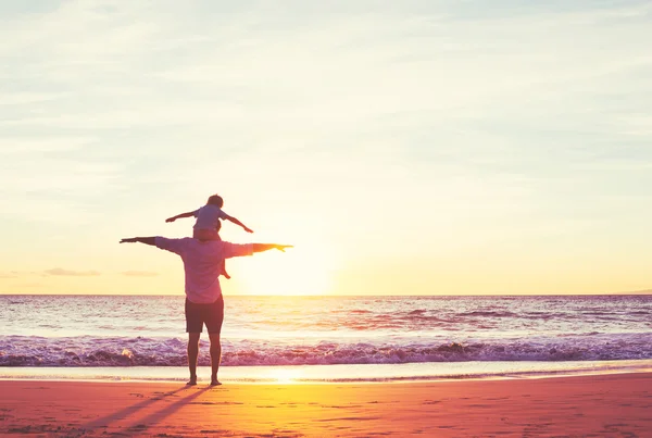 Pai e filho brincando na praia ao pôr do sol — Fotografia de Stock