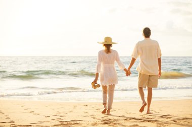 Olgun çift gün batımında sahilde yürüyüş