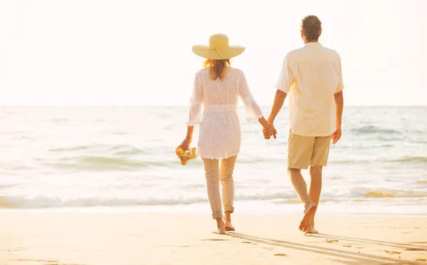 成熟夫妻在日落时分在沙滩上散步 — 图库照片