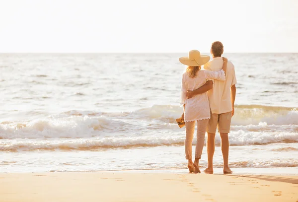 Pareja madura caminando en la playa al atardecer — Foto de Stock