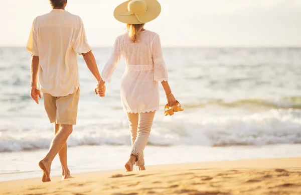 Casal maduro andando na praia ao pôr do sol — Fotografia de Stock