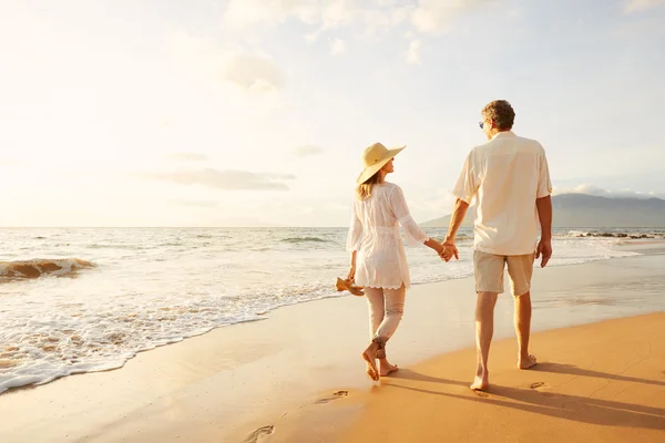 Äldre par promenader på stranden vid solnedgången — Stockfoto