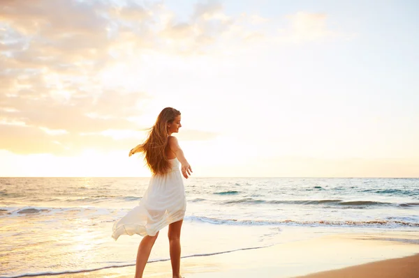 Happy sorglös kvinna på stranden vid solnedgången — Stockfoto