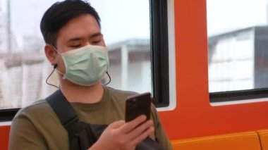 Maske takan bir adamın POV 'u Skytrain banliyösünde otururken cep telefonu kullanırken Corona virüsünden korunuyor.