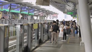 Yaklaşan treni bekleyen yolcularla dolu BTS tren istasyonunun manzara görüntüsü.