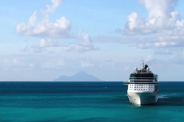 Kreuzfahrtschiff mit Insel im Hintergrund lizenzfreie Stockbilder