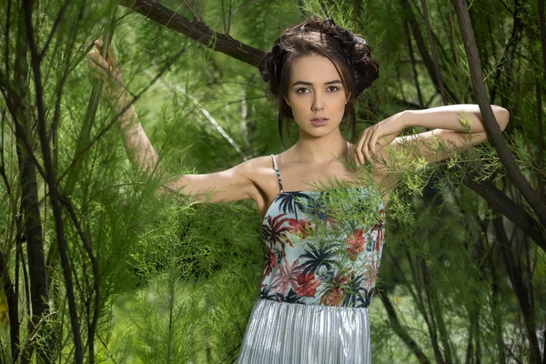 Girl in a dress stands between trees — Stock Photo, Image