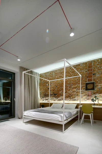 Yatak odasında bir modern loft tarzı. Tuğla duvar sıva olmadan. Yatak — Stok fotoğraf