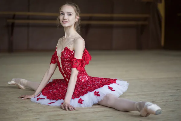 Bailarina sentada no chão nas fendas curativo em tut vermelho — Fotografia de Stock