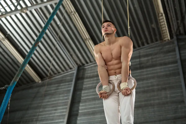 Atleta topless faz um exercício difícil em anéis de ginástica em — Fotografia de Stock