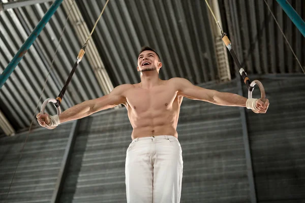 Atleet topless maakt een moeilijke oefening op gymnastiek ringen in — Stockfoto