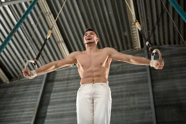 Atleta topless faz um exercício difícil em anéis de ginástica em — Fotografia de Stock