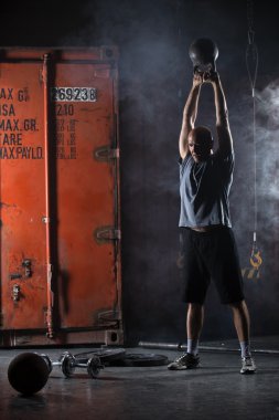 Kel karizmatik atlet kettlebell salıncaklar yapıyor. Vurulmuş stüdyo
