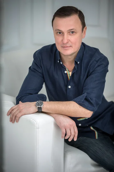 Man sitting in the sofa with a slight smile — Stock Photo, Image