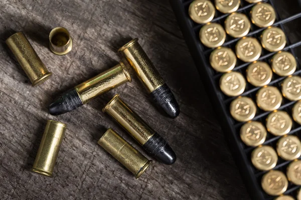 Scattering of small caliber cartridges on a wooden background — Stock Photo, Image