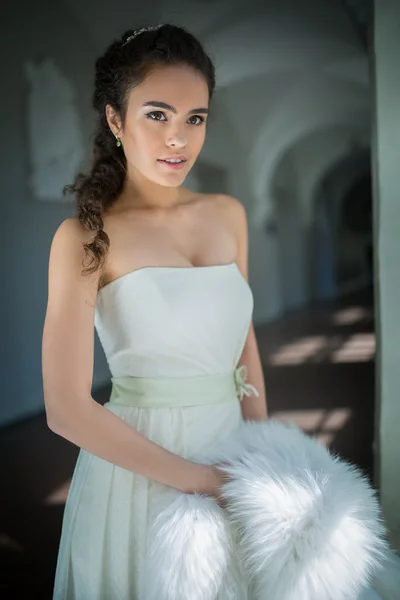 Zarte Braut mit lockigem Haar steht am Fenster — Stockfoto