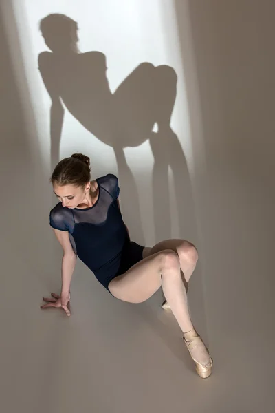 Fullängds porträtt sitter på golvet i en graciös ballerin — Stockfoto