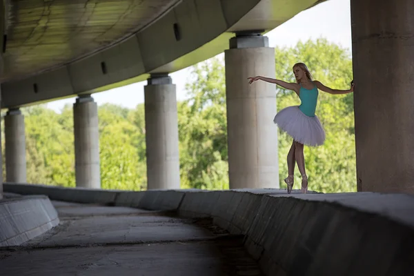 Graceful ballerina doing dance exercises on a concrete bridge — Stock Photo, Image