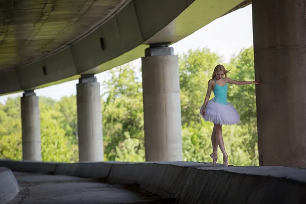 Витончена балерина виконує танцювальні вправи на бетонному мосту — стокове фото