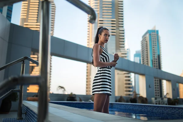 Beautiful brunette in a striped dress — Stock Photo, Image