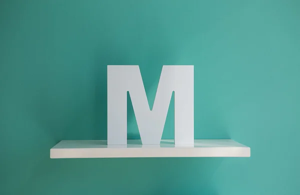 Letter M turquoise color on a white shelf. — Stock Fotó