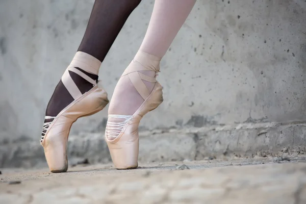 Ballerina-Füße in Nahaufnahme auf einem Hintergrund aus strukturiertem Beton — Stockfoto