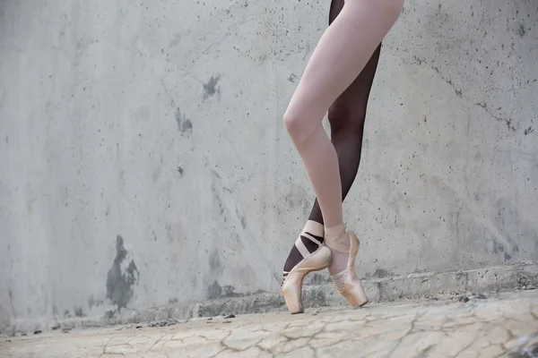 Pés de bailarina close-up em um fundo de wal de concreto texturizado — Fotografia de Stock